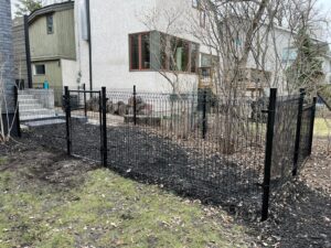 Black welded wire fence with gate enclosing patio stair access and backyard in urban yard